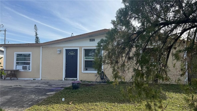 view of front of house with a patio, cooling unit, and a front lawn