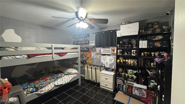 bedroom featuring a textured ceiling, dark tile patterned floors, and ceiling fan