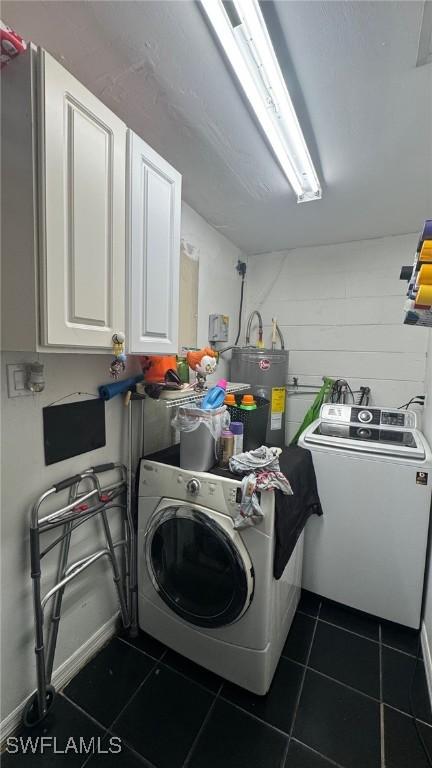 laundry room with water heater, independent washer and dryer, cabinets, and dark tile patterned floors