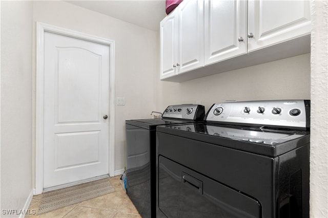 laundry room featuring washer and clothes dryer, cabinets, and light tile patterned floors