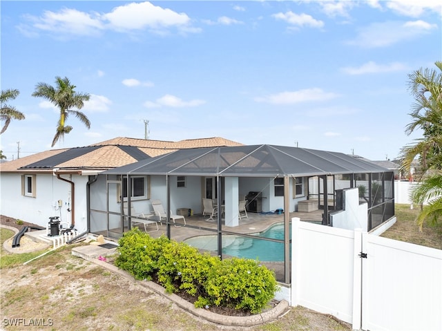 rear view of property featuring a lanai, a fenced in pool, and a patio area