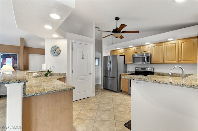 kitchen featuring lofted ceiling, kitchen peninsula, light stone countertops, and stainless steel appliances