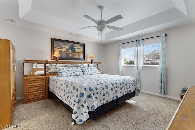 carpeted bedroom featuring ceiling fan and a tray ceiling