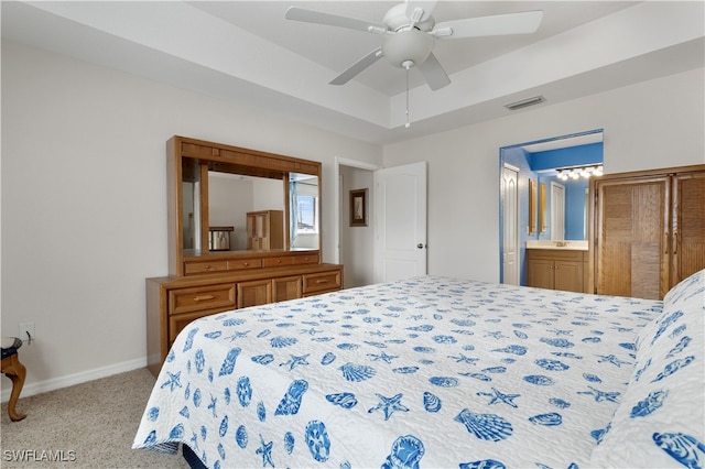 bedroom with light carpet, ceiling fan, connected bathroom, and a raised ceiling