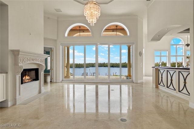 living room with a water view, a fireplace, an inviting chandelier, and ornamental molding