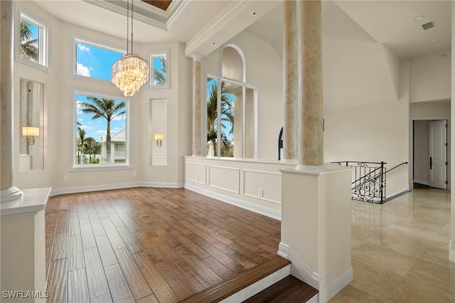 interior space with visible vents, wood finished floors, a high ceiling, and decorative columns