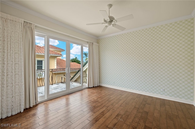 empty room with wallpapered walls, crown molding, and baseboards