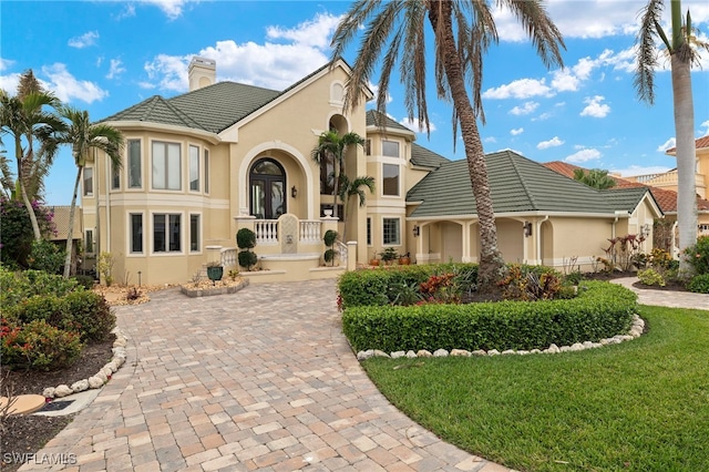 mediterranean / spanish-style home with a chimney, stucco siding, french doors, and a tile roof