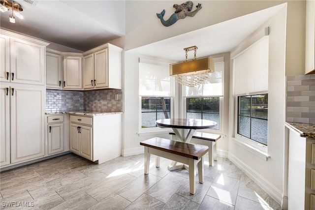 kitchen featuring light stone countertops, pendant lighting, and backsplash