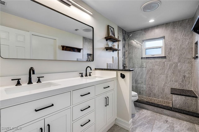 bathroom with tiled shower, vanity, and toilet