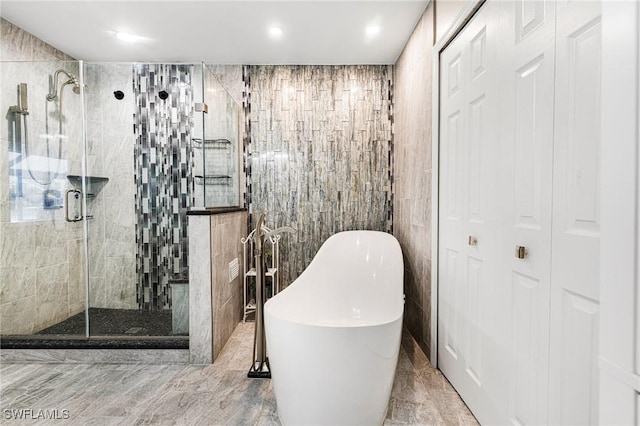 bathroom featuring plus walk in shower and tile walls