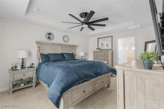 bedroom featuring connected bathroom, a raised ceiling, ceiling fan, and light tile patterned flooring