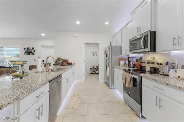 kitchen featuring light stone counters, appliances with stainless steel finishes, sink, and white cabinets