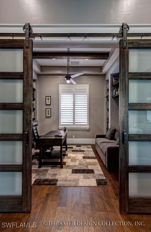 living room with built in features, hardwood / wood-style flooring, beam ceiling, and a barn door