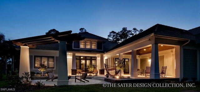 back house at dusk with a patio area and a fire pit