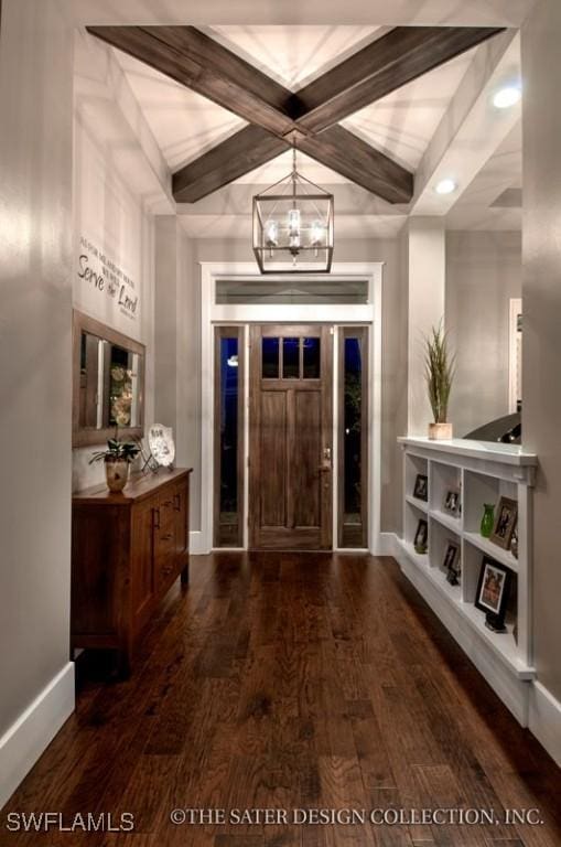 foyer entrance featuring coffered ceiling, dark wood-type flooring, beamed ceiling, and an inviting chandelier