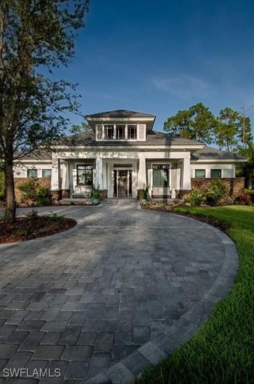 prairie-style house featuring a front yard, decorative driveway, and stucco siding