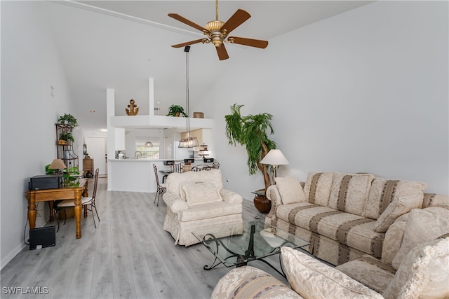 living room with ceiling fan, light hardwood / wood-style floors, and a towering ceiling