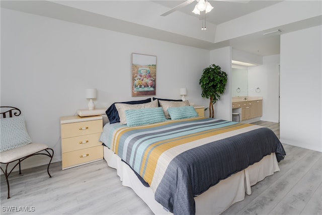 bedroom featuring ceiling fan, ensuite bath, and light wood-type flooring