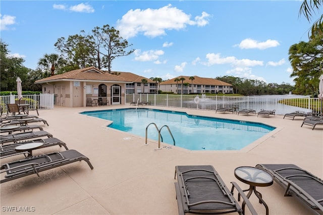 view of pool featuring a water view and a patio area