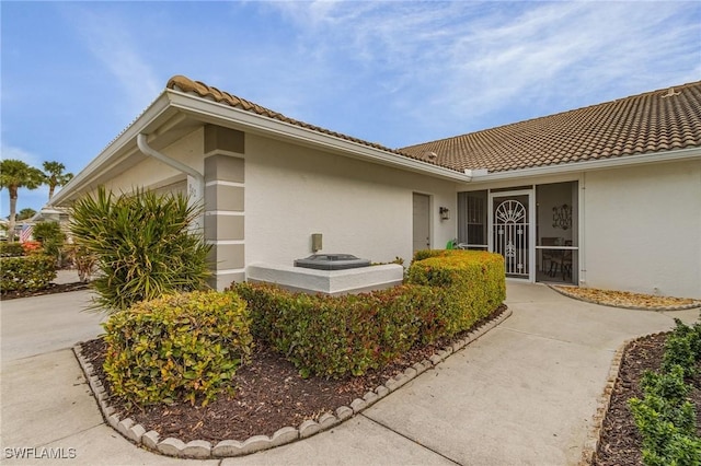 doorway to property with concrete driveway, stucco siding, a garage, and a tile roof