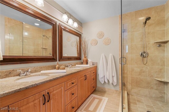 bathroom with a shower with shower door, tile patterned floors, and vanity