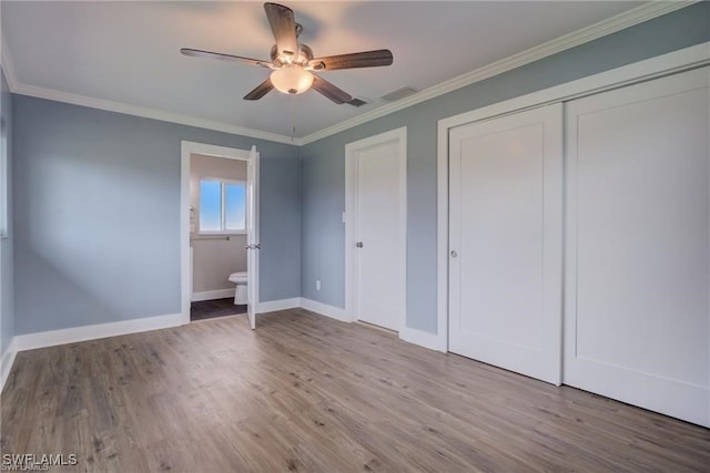 unfurnished bedroom with connected bathroom, ornamental molding, a closet, hardwood / wood-style flooring, and ceiling fan