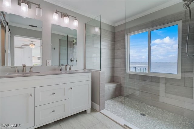 bathroom with tiled shower, a water view, ornamental molding, vanity, and ceiling fan