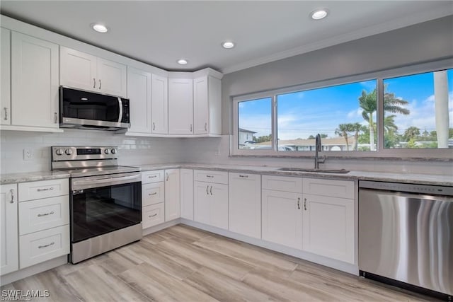 kitchen featuring sink, white cabinetry, backsplash, stainless steel appliances, and light stone countertops