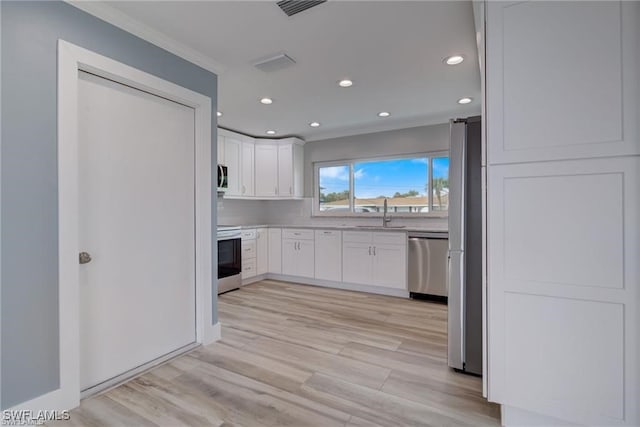 kitchen featuring sink, crown molding, stainless steel appliances, light hardwood / wood-style floors, and white cabinets