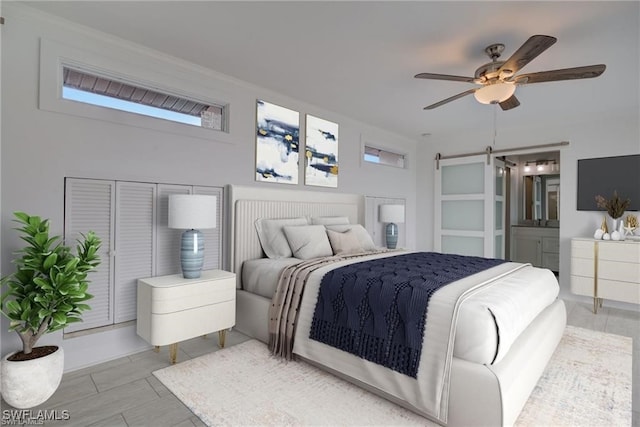 bedroom featuring ensuite bath, a barn door, and ceiling fan