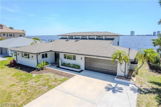 view of front facade with a garage, a front yard, and a water view