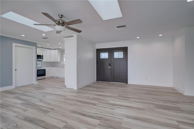 interior space with ornamental molding, light hardwood / wood-style flooring, ceiling fan, and a skylight