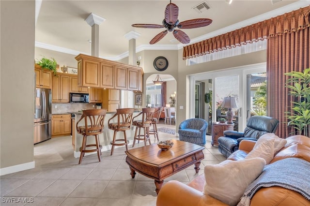 tiled living room with ceiling fan, ornamental molding, and a towering ceiling