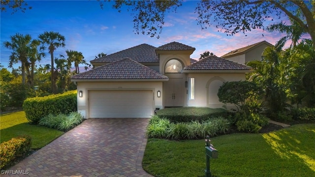 mediterranean / spanish-style house featuring a garage and a yard