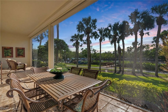 patio terrace at dusk featuring a lawn