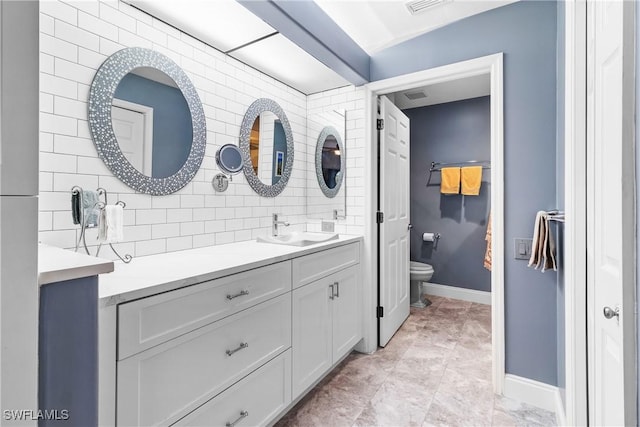 bathroom featuring toilet, vanity, and tasteful backsplash