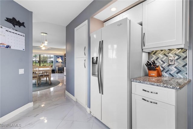 kitchen with tasteful backsplash, white fridge with ice dispenser, stone counters, and white cabinetry