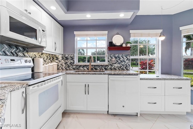 kitchen with light stone countertops, white appliances, white cabinetry, tasteful backsplash, and sink