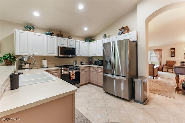 kitchen with white cabinets, lofted ceiling, stainless steel appliances, sink, and light tile patterned flooring