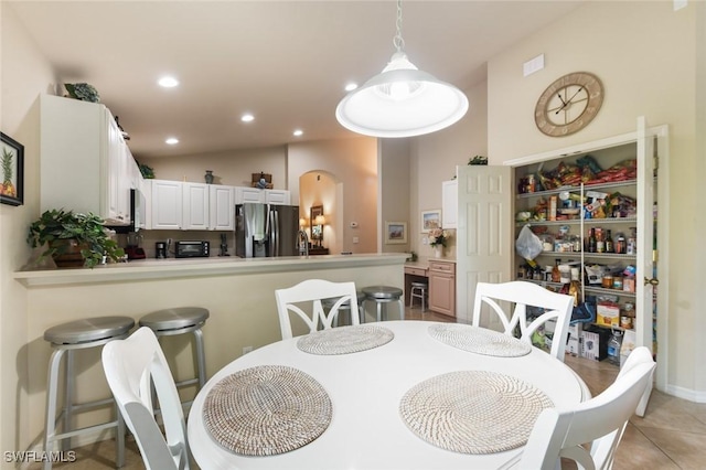 dining space featuring vaulted ceiling and light tile patterned floors