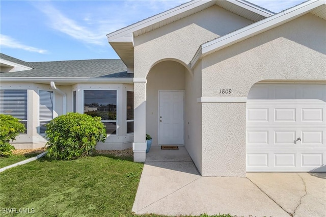 view of exterior entry with a garage and a lawn