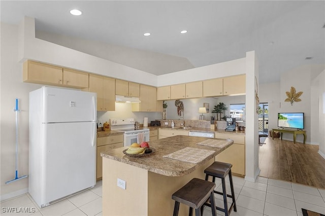 kitchen featuring lofted ceiling, a kitchen island, a kitchen bar, white appliances, and light tile patterned floors