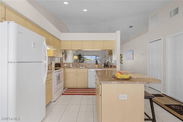 kitchen featuring white appliances, a center island, a kitchen bar, light brown cabinets, and sink