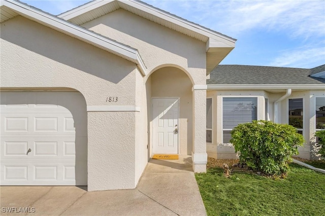 entrance to property featuring a lawn and a garage