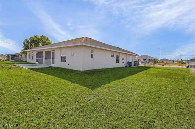 rear view of property featuring central AC, a lawn, and a patio