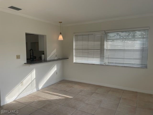 unfurnished room featuring light tile patterned floors and ornamental molding