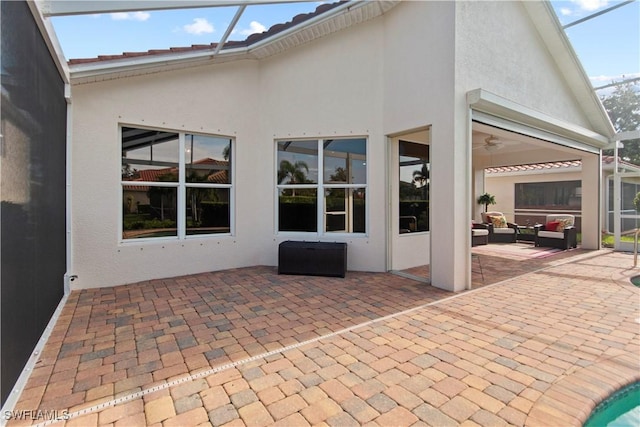 view of patio / terrace with an outdoor living space, ceiling fan, and glass enclosure