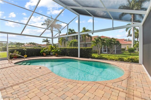 view of swimming pool featuring glass enclosure and a patio area