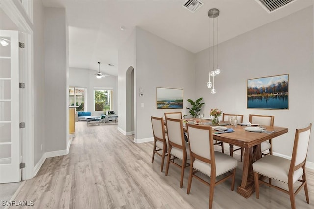 dining space with ceiling fan, high vaulted ceiling, and light hardwood / wood-style flooring